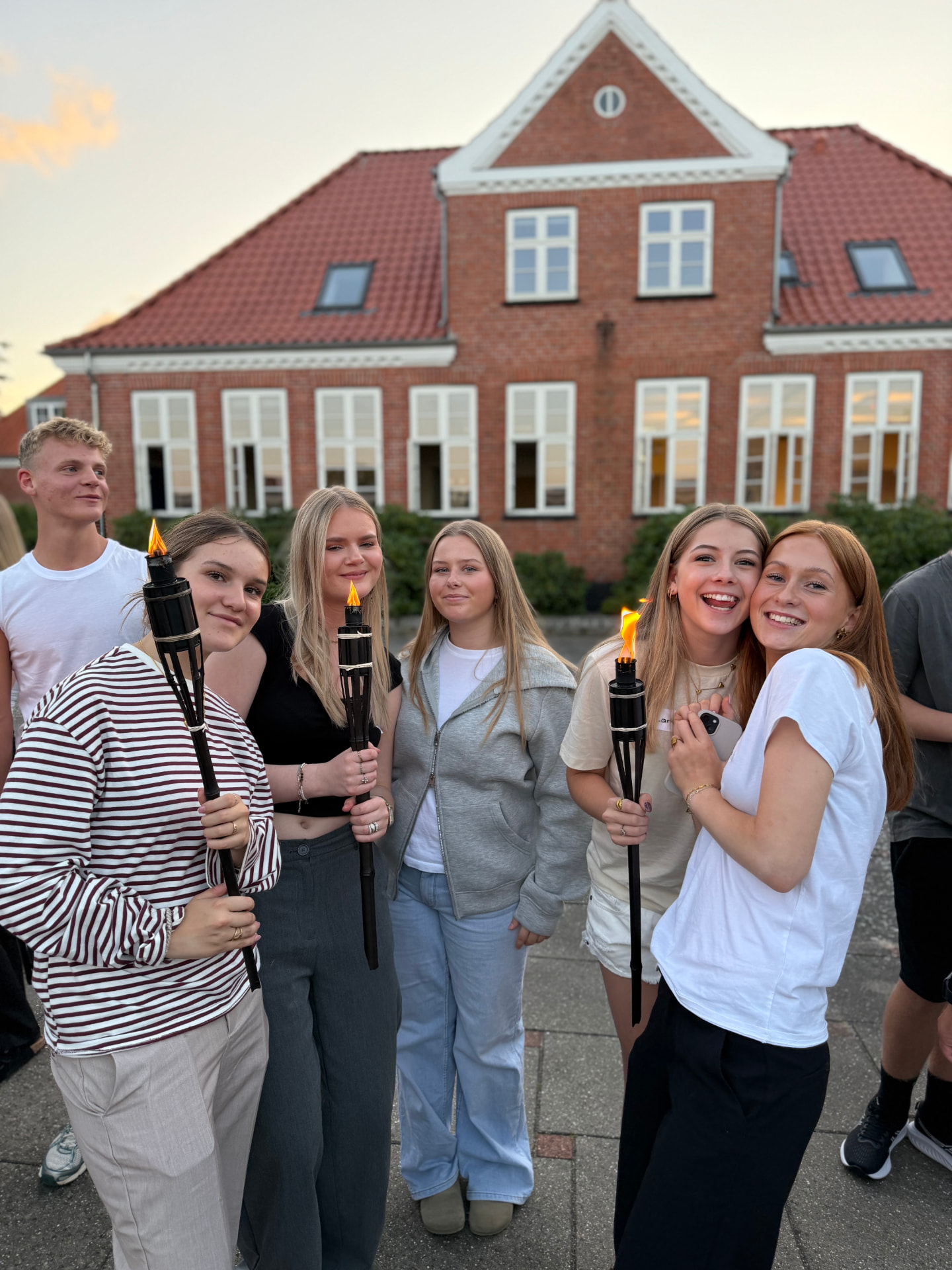 Elever med fakler foran skolen